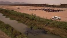 Inmigrantes cerca del muro fronterizo después de cruzar el río Bravo