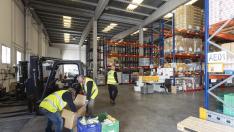 Tres voluntarios del banco de alimentos de Zaragoza mueven cajas en el almacén de la ciudad.