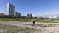 Una mujer pasea por los terrenos cercanos a la avenida de Ciudad de Soria, con dos torres de edificios al fondo.