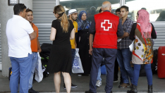 Imagen de archivo de un miembro de Cruz Roja con un grupo de refugiados en el aeropuerto de Madrid-Barajas.