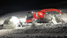 Una máquina transportando de noche nieve de fuera de pistas a la zona de La Tuca en Candanchú.