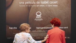 Dos mujeres se saludan junto a uno de los carteles de las películas que se proyectan en el 71 Festival Internacional de Cine de San Sebastián