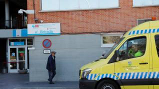 A man walks past an ambulance as he leaves Hospital Carlos III, where a case of novel coronavirus has been confirmed, in Madrid