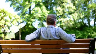 Un hombre jubilado sentado en un banco.