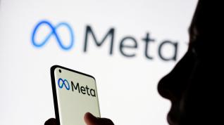 FILE PHOTO: Woman holds smartphone with Meta logo in front of a displayed Facebook's new rebrand logo Meta in this illustration picture