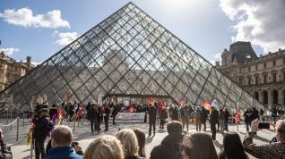 Visitantes esperan fuera del Museo del Louvre mientras los empleados bloquean la entrada.