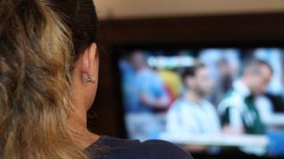 Una mujer viendo un partido de fútbol en una televisión