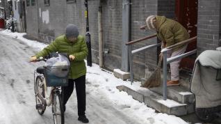 Beijing (China), 11/12/2023.- A woman pushes her bicycle along a street covered in snow in Beijing, China, 11 December 2023. Beijing has its first snowfall this winter as in the northern regions, China'Äôs Meteorological service has issued a yellow alert for blizzards. EFE/EPA/ANDRES MARTINEZ CASARES