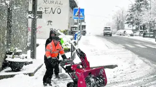 Un operario trata de retirar nieve en Villanúa que, como muchas localidades del Pirineo, amaneció ayer completamente nevada.