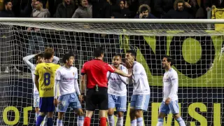 Los jugadores del Real Zaragoza protestan a Díaz de Mera, árbitro del partido del pasado lunes en Cádiz, la decisión del penalti que supuso el 3-3 final ya con el tiempo concluido.