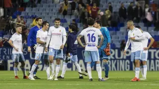 Parte de los futbolistas del Real Zaragoza, cariacontecidos, nada más concluir el partido de este domingo ante el Alcorcón con derrota por 0-2 en La Romareda, escuchan la bronca de la afición.