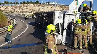 Los bomberos rescatan al conductor de un camión que quedó atrapado tras volcar en la Z-40