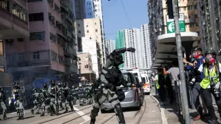 Un policía lanza una granada de gas contra manifestantes en una calle de Hong Kong.