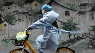 Una mujer en bici se protege del coronavirus en Wuhan, epicentro de la epidemia en China
