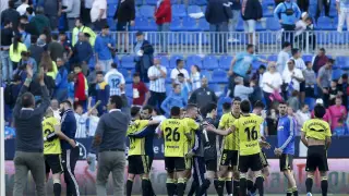 Jugadores, técnicos y auxiliares del Real Zaragoza celebran sobre el césped la victoria en Málaga, saludando a la afición aragonesa que había en las gradas.