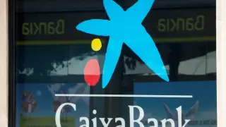 FILE PHOTO: Logos of Caixabank and Bankia are seen in bank offices near Barcelona