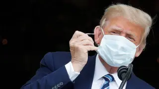 El presidente estadounidense Donald Trump se retira la mascarilla en su primera aparición pública tras estar ingresado.