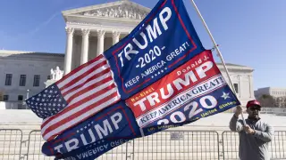 Un seguidor de Trump ondea una bandera de Estados Unidos delante del Tribunal Supremo, en Washington.
