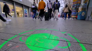 Un dibujo en el suelo recuerda la obligación de llevar mascarilla en una calle comercial de Colonia, Alemania.
