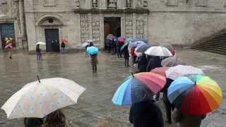 Varias personas aguardan bajo la lluvia para entrar a la catedral de Santiago por la Puerta Santa