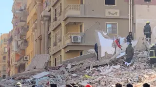 People inspect the area where a building was collapsed in Gesr al-Suez, Cairo