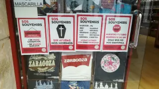 Carteles denunciando la difícil situación económica que atraviesa el sector, en el escaparate de una tienda de Zaragoza.