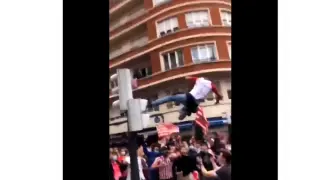Imagen de un aficionado del Athletic saltando desde un semáforo entre la multitud, en Bilbao.