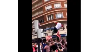 Imagen de un aficionado del Athletic saltando desde un semáforo entre la multitud, en Bilbao.
