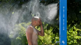 Un hombre se refresca en un nebulizador colocado en una calle de Vancouver