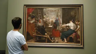 Un visitante observa "Las hilanderas" de Velázquez, que puede contemplarse desde este lunes en el Museo del Prado tal y como Velázquez quiso que se viera