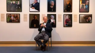 John Hajdu, superviviente del Holocausto, posa delante de varios retratos de la exposición.