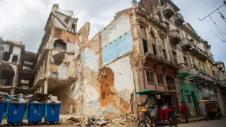 Un bicitaxi pasa frente a un edificio en ruinas, en una de las calles de La Habana Vieja, este viernes.