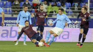 Salvador se tira al césped para frenar a un rival durante el duelo entre la SD Huesca y el Ibiza.