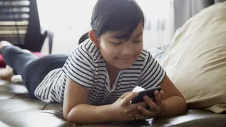 Una niña usando un móvil.