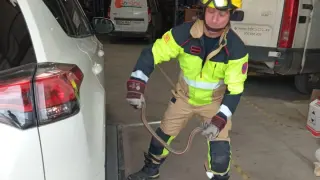 Un bombero de la DPT retira un culebra bomberos del bajo de un coche en una nave de Teruel