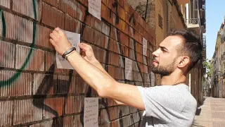 Caio Machado, colocando un cartel en la pared de la tapia ubicada en el solar del número 11 de la calle Casta Álvarez de Zaragoza