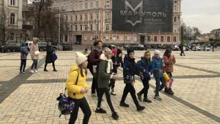 Un grupo de estudiantes se dirigen a la exposición ante un cartel recordando la hazaña de Mariupol