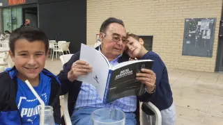 Manuel Martín de Urrea con dos de sus nietos: Sergio y Juan, al que abraza. Lleva en las manos el libro sobre el Real Zaragoza que publicó HERALDO en 2021.