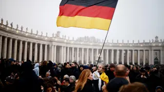 Un asistente al funeral del papa emérito sostiene la bandera de Alemania.