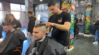 Los alumnos de la Escuela de barbería del Tío Jorge practican con algunos clientes.