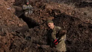 Un soldado ucraniano cava una trinchera en el frente de Bajmut mientras otro compañero vigila.