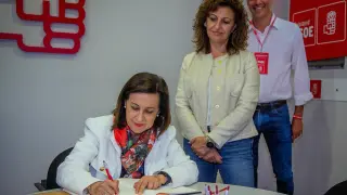 Margarita Robles firma en el libro en la sede del PSOE de Calatayud, junto a la candidata a la Alcaldía Sandra Marin, este viernes.