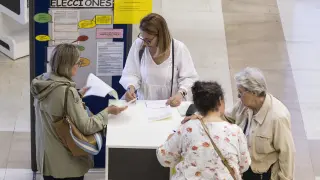 Varias personas rellenan una solicitud para pedir el voto por correo en la oficina del paseo de la Independencia.