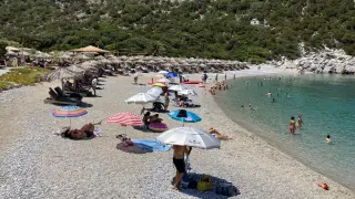 Varias personas toman el sol en una playa de la isla griega de Skópelos, en las Espóradas.