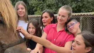 La reina Letizia y sus hijas, acompañadas de un grupo de niños, durante la visita este viernes a la Granja Escuela Jovent.