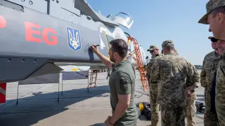 Volodímir Zelenski estampa su firma en un avión de combate, en el Día de las Fuerzas Armadas de Ucrania, este domingo.