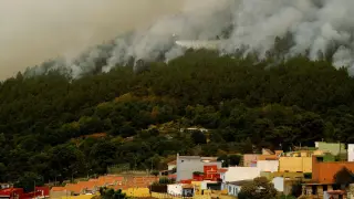 Un helicóptero de extinción de incendios descarga agua cerca de Aguamansa, mientras las llamas avanzan sin control.