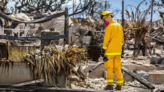 Un miembro del servicio de rescate examina los restos de una zona devastada por el fuego en Lahaina, Hawái.