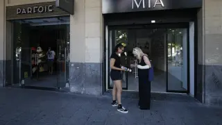 Una trabajadora de la tienda Mía, en el paseo de la Independencia, enseña a una clienta varias pulseras en la calle.