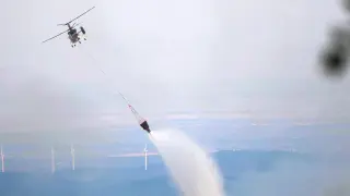 Un helicóptero de extinción de incendios arroja agua durante los esfuerzos para apagar incendios forestales en la zona de Leptokarya, Evros, al norte de Grecia.